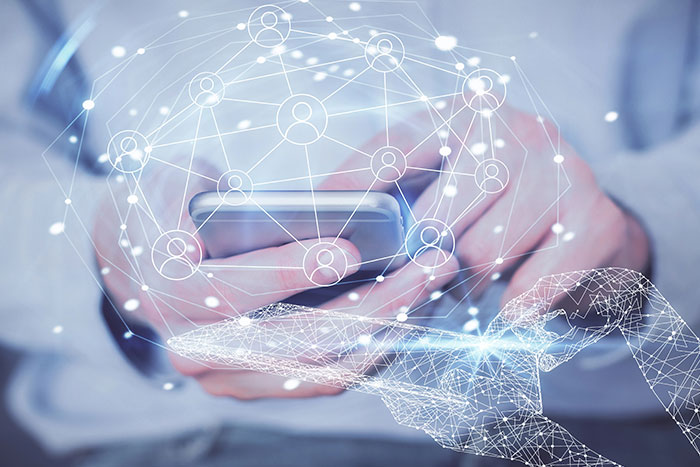 Hands holding a smartphone with an overlay of a digital network of interconnected lines and person icons.