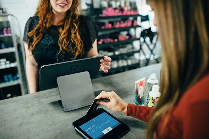 A customer swiping a card on a digital payment terminal at a store counter.